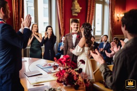   In Lyon, Rhône, France, the couple exchanges vows at city hall, surrounded by the applause of their guests and illuminated by the inviting glow of warm light.